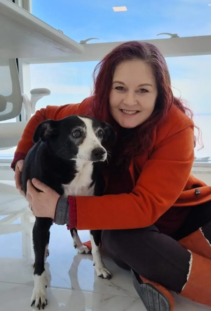 Dra. Flávia Howes sorrindo e abraçando um cão preto e branco